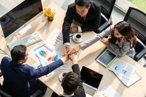 Happy business people celebrate teamwork success Happy business people celebrate teamwork success together with joy at office table shot from top view . Young businessman and businesswoman workers express cheerful victory showing unity and support .